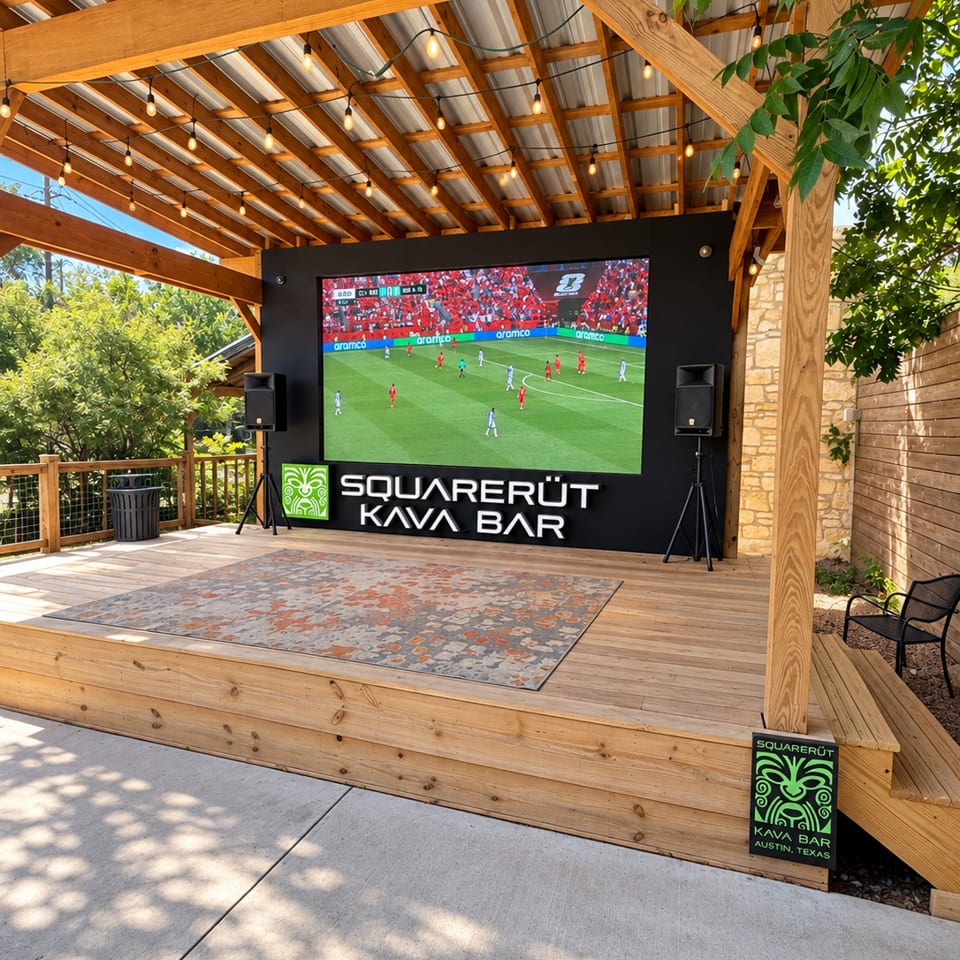 Outdoor Squarerut Kava Bar patio with a large soccer-screening television, speakers, string lights, and wooden seating.